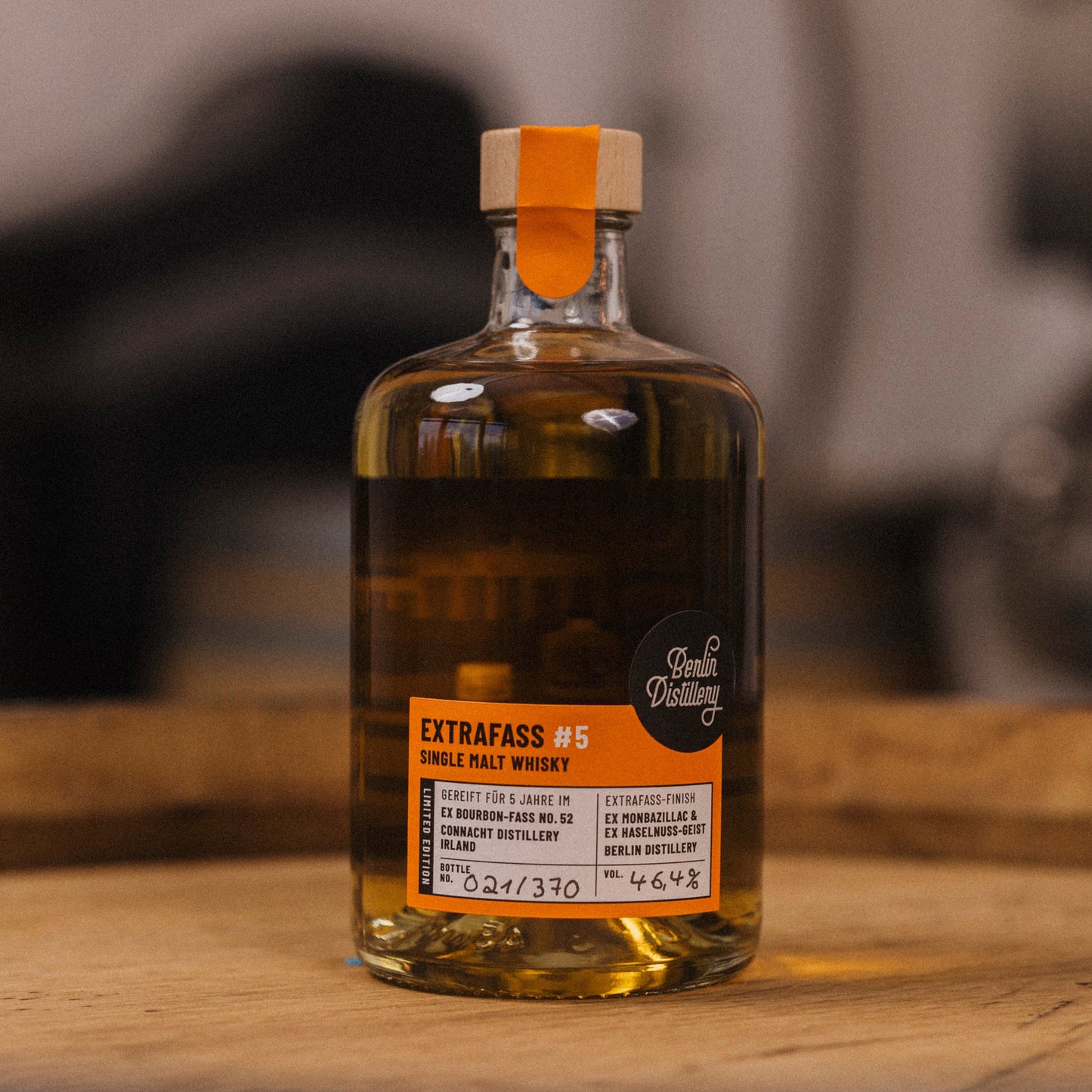 Eine Flasche EXTRAFASS #5 Single Malt Whisky der Berlin Distillery steht zusammen mit einem gefüllten Nosingglas auf einem Whiskyfass.