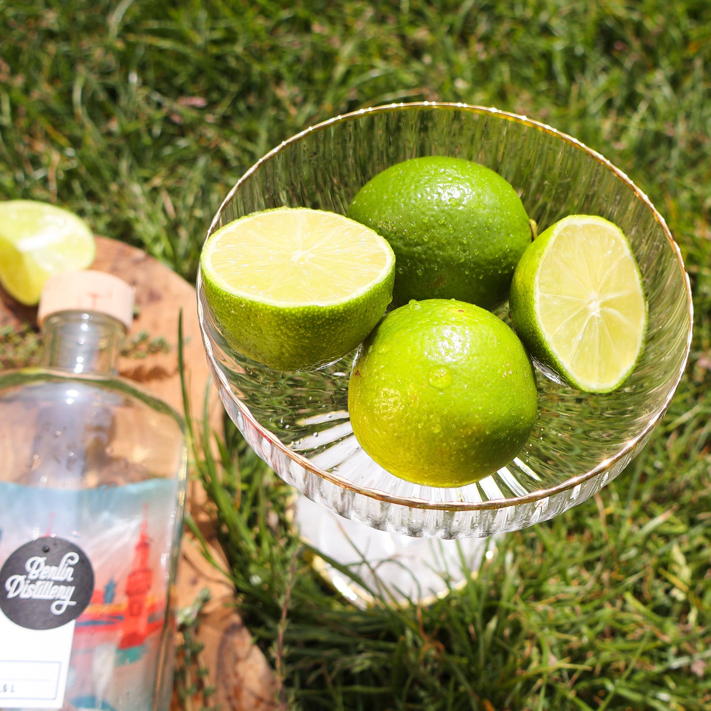 Frische Limetten in einer Schale neben einer Gin-Flasche der Berlin Distillery.