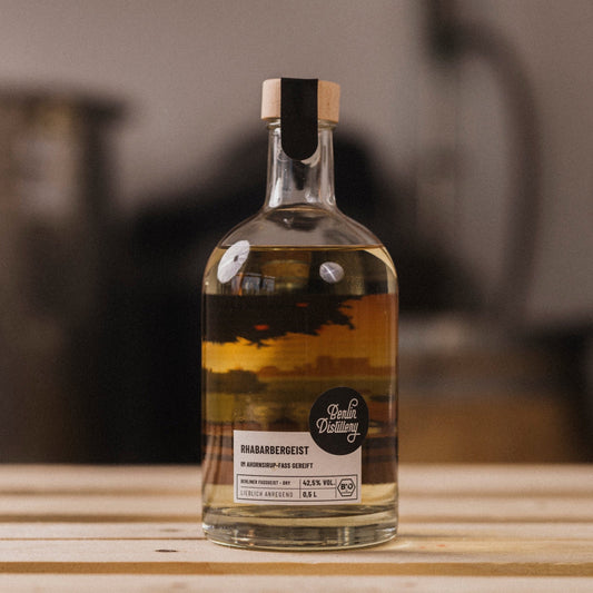 Eine Flasche Berlin Distillery Rhabarber Fassgeist steht auf einer Holzpalette vor dem Hintergrund der Produktionseinrichtung.