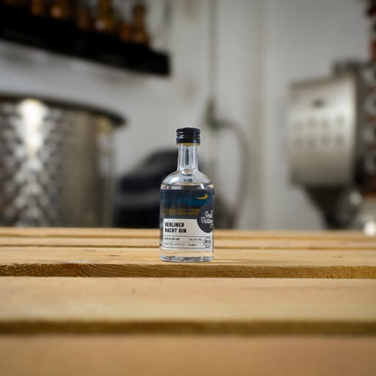 Eine Flasche Berlin Distillery Berliner Nacht Gin steht auf einer Holzpalette vor der Produktionsanlage.