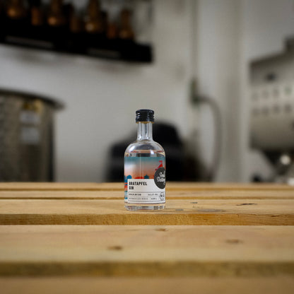 Eine kleine Flasche Berlin Distillery Bratapfel Gin steht auf einer Holzpalette vor der Produktionsanlage.