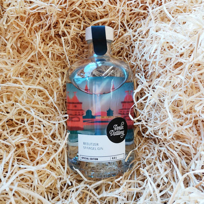 Eine Flasche Berlin Distillery Spargel Gin liegt in Holzwolle.